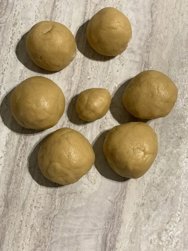 Seven balls of honey cake dough arranged on a countertop