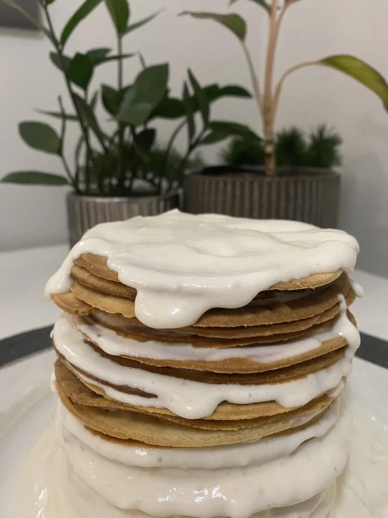 Stack of thin Medovik honey cake layers with creamy filling dripping between each layer