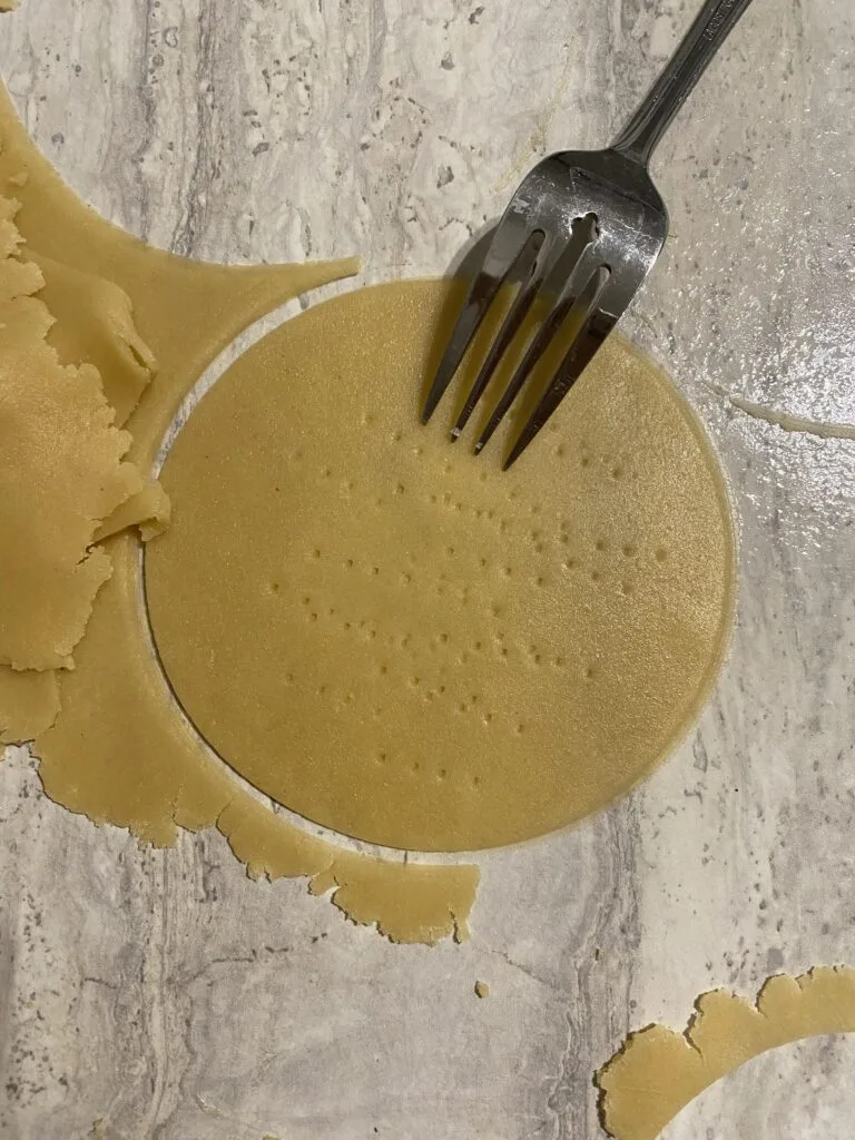 Round honey cake dough piece pricked with a fork, ready for baking