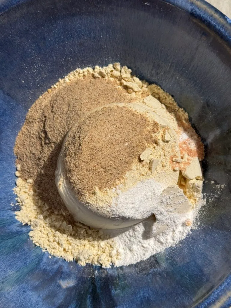 A bowl filled with dry ingredients for gluten-free Christmas cookies, including flour, psyllium husk, salt, and baking powder, ready to be mixed.