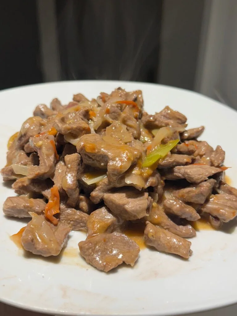 Stir-fried beef served hot on a plate with a light sauce.