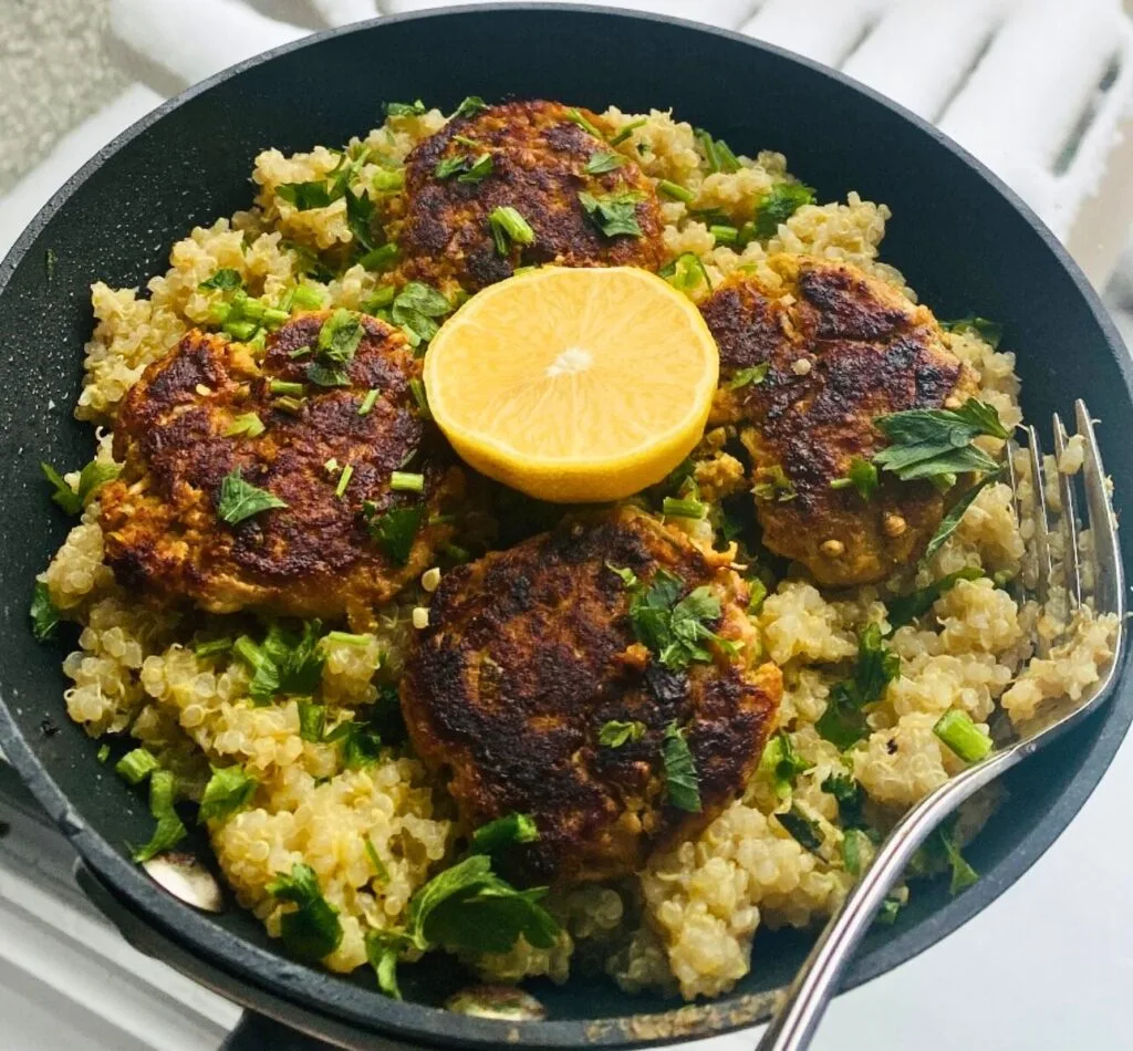 Crispy fish cutlets served over quinoa, garnished with fresh herbs and lemon.