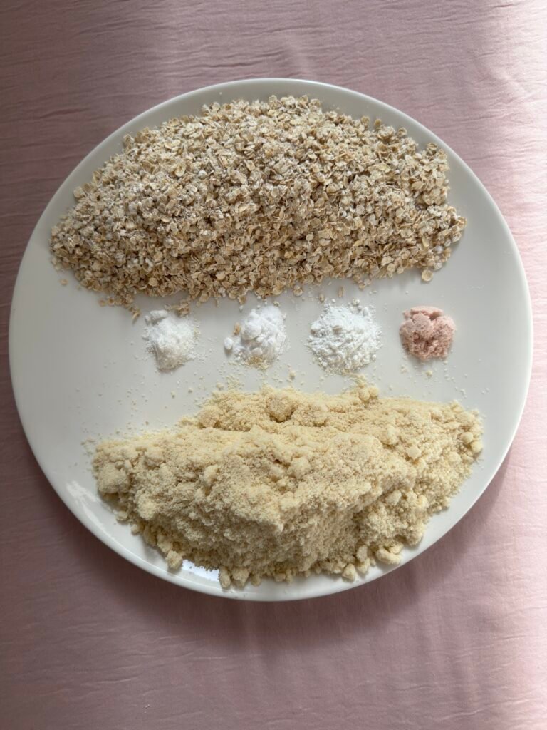 Dry ingredients for gluten-free monster cookies: gluten-free oats, almond flour, baking powder, baking soda, vanilla powder, and pink Himalayan salt.