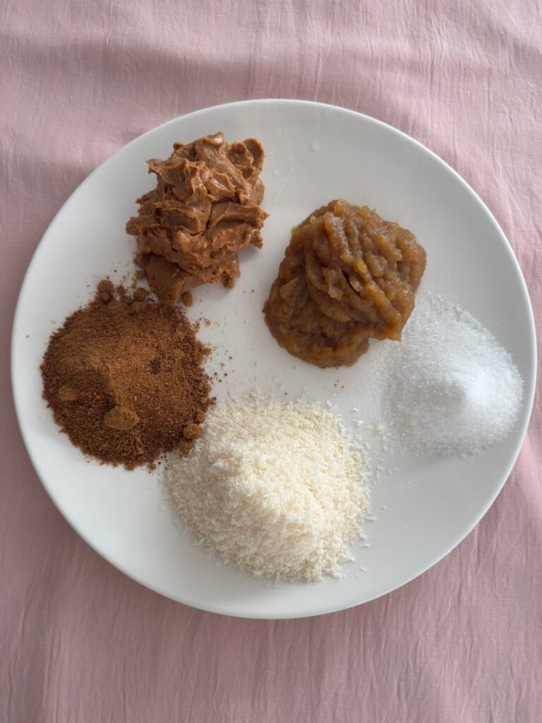 Wet ingredients for monster cookies on a plate: peanut butter, applesauce, coconut sugar, granulated sugar, and desiccated coconut.