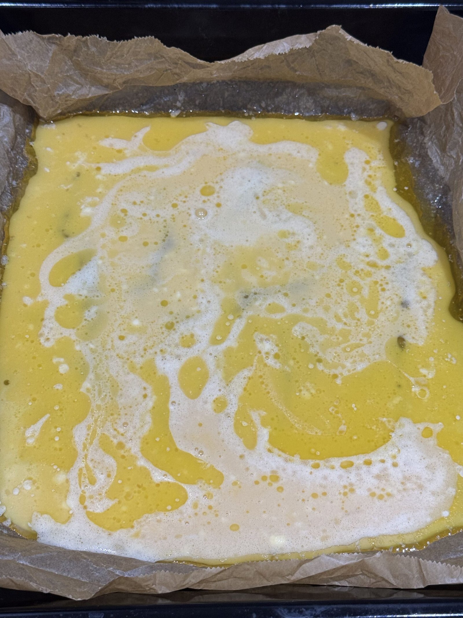 Gluten-free Dutch baby batter just poured into the hot buttered baking tray, swirling together with melted butter