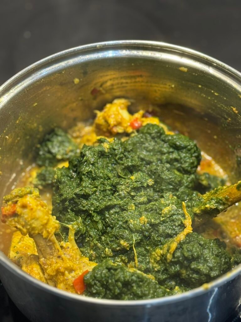 Blended spinach paste added on top of the cooked chicken and masala in the pot.