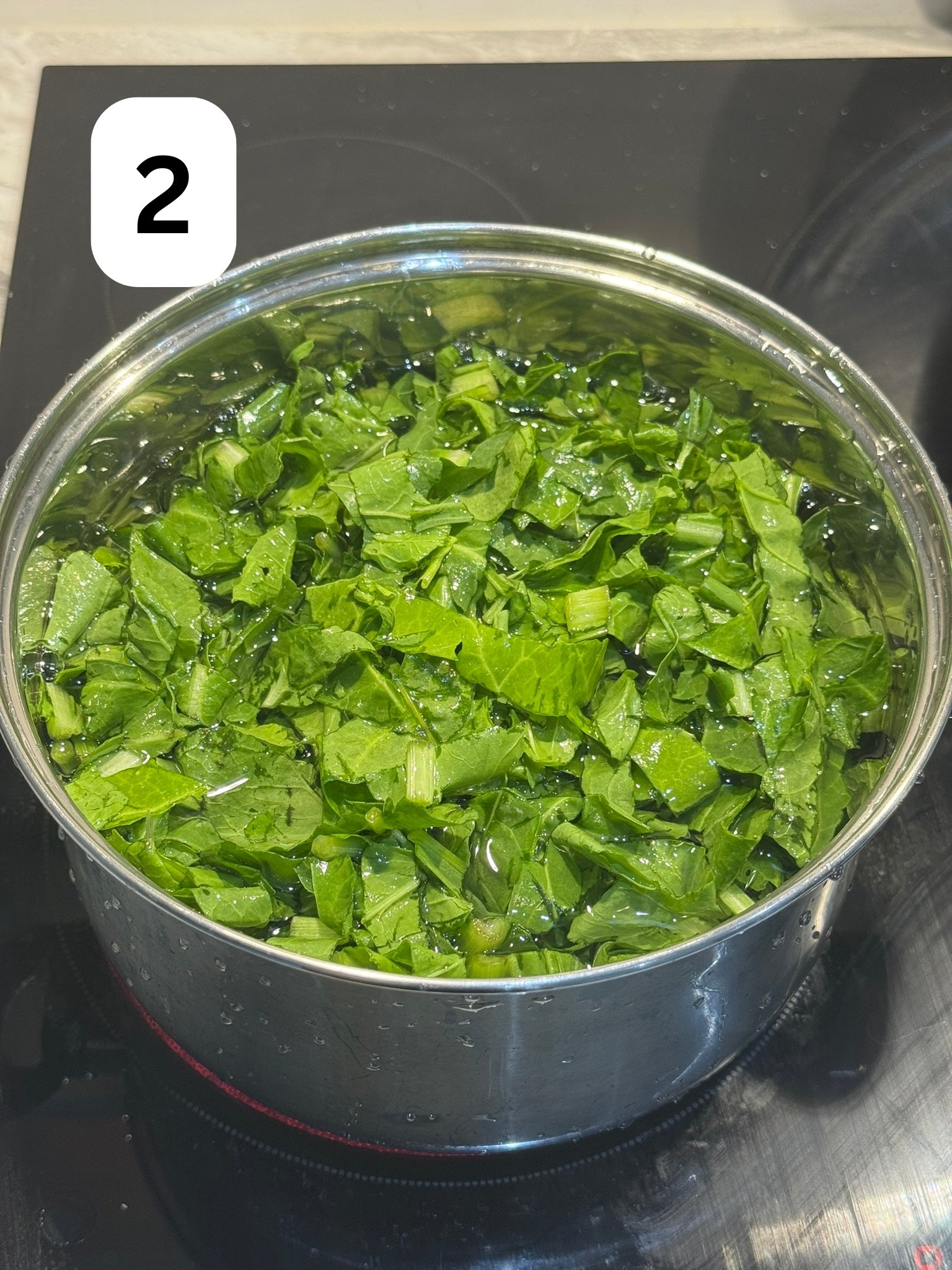 Chopped spinach blanching in a pot of boiling water on the stove.
