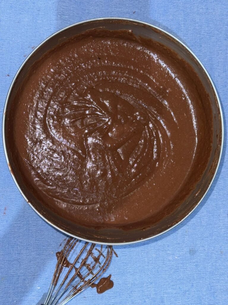 Smooth chocolate cake batter spread evenly in a round pan before baking.