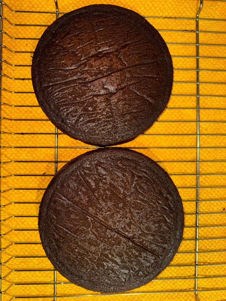 Two round gluten-free chocolate cake layers cooling on a wire rack.