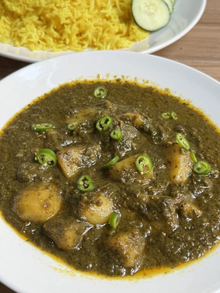 Close-up of aloo palak curry garnished with sliced green chilies