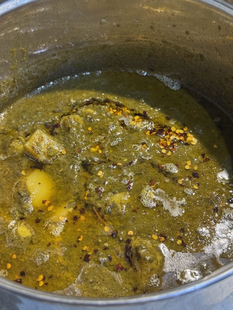 Sizzling ghee and chili flake tarka poured over the finished potato and spinach curry