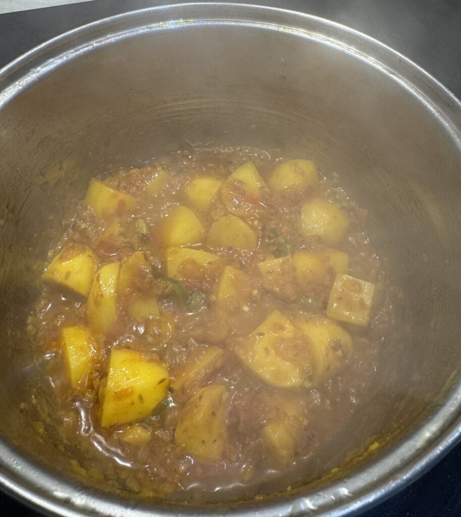 Cubed potatoes coated in turmeric, coriander, and red chili powder in the pot