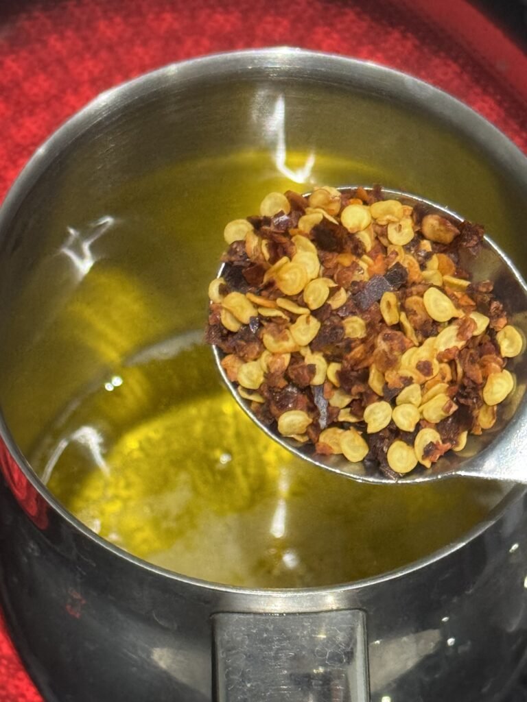 Red chili flakes blooming in hot desi ghee for the tarka finish